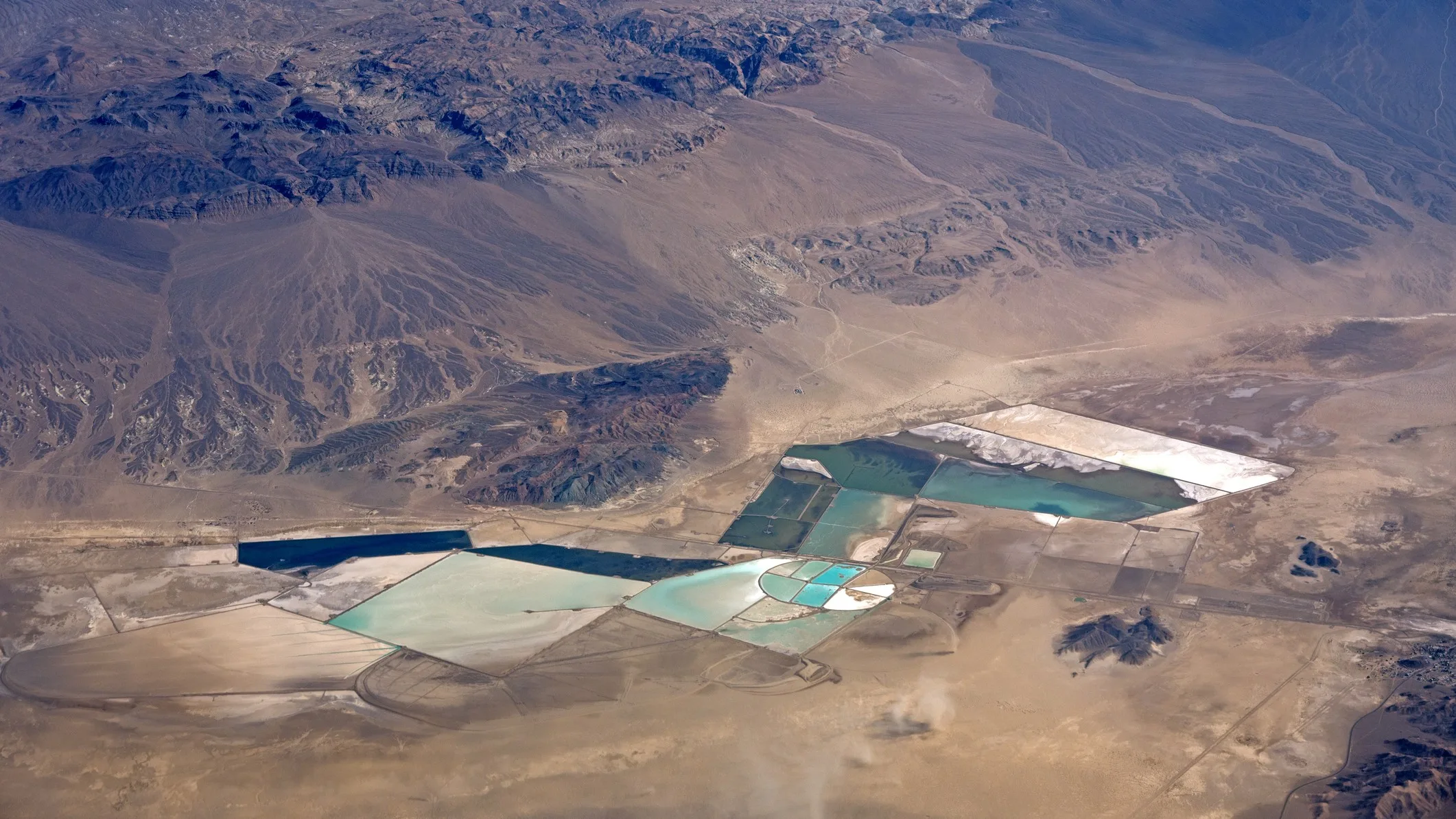 Aerial view of the Silver Peak lithium mine in Nevada. We see light blue basins in a parched landscape.